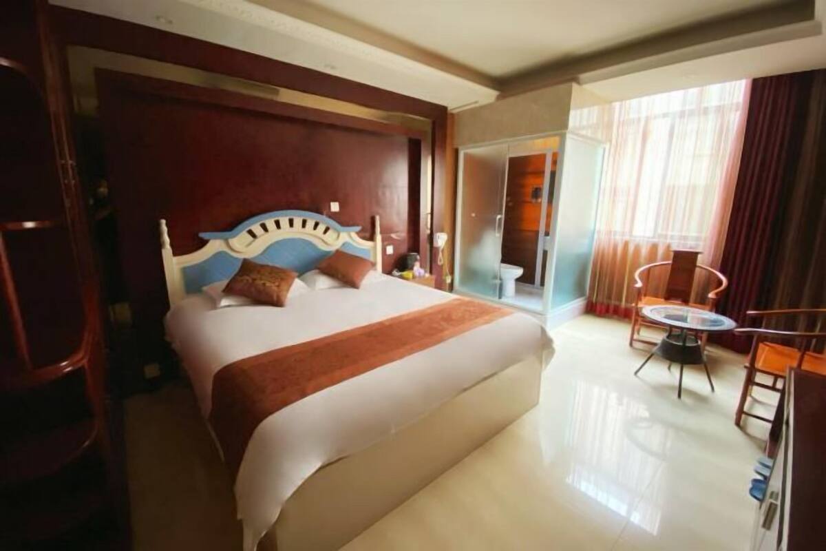 A hotel room with a large bed, a small round table, and a separate bathroom area.