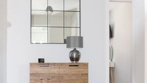 Un mueble de madera con una lámpara, un altavoz pequeño y un espejo en la pared.