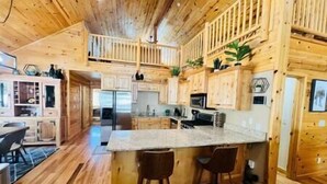 A spacious kitchen with wooden cabinets, a large island with bar stools, and a view of the living area.