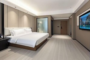 A modern hotel room with a large bed, a nightstand, a TV, and a door leading to another room. - Chibi Lake Holiday Hotel (Xinjiekou Commercial Street) (Chibi)