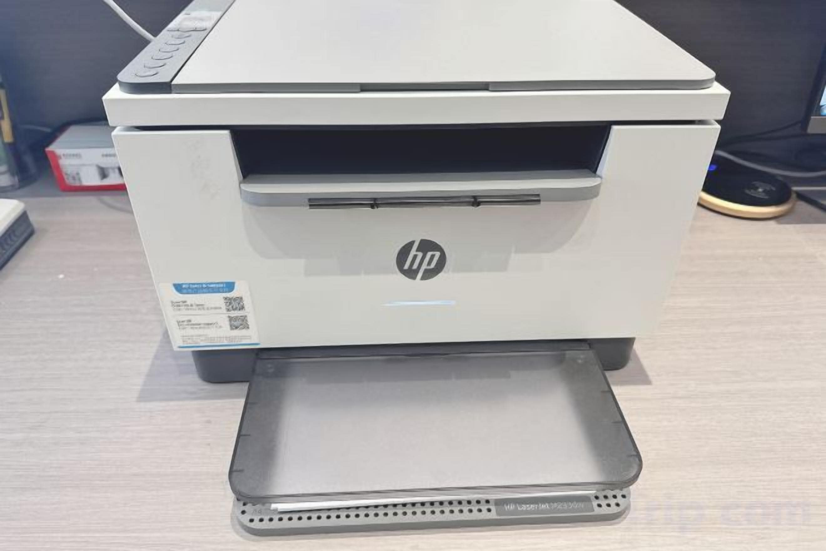Una impresora con el logotipo de HP, una etiqueta y una bandeja.