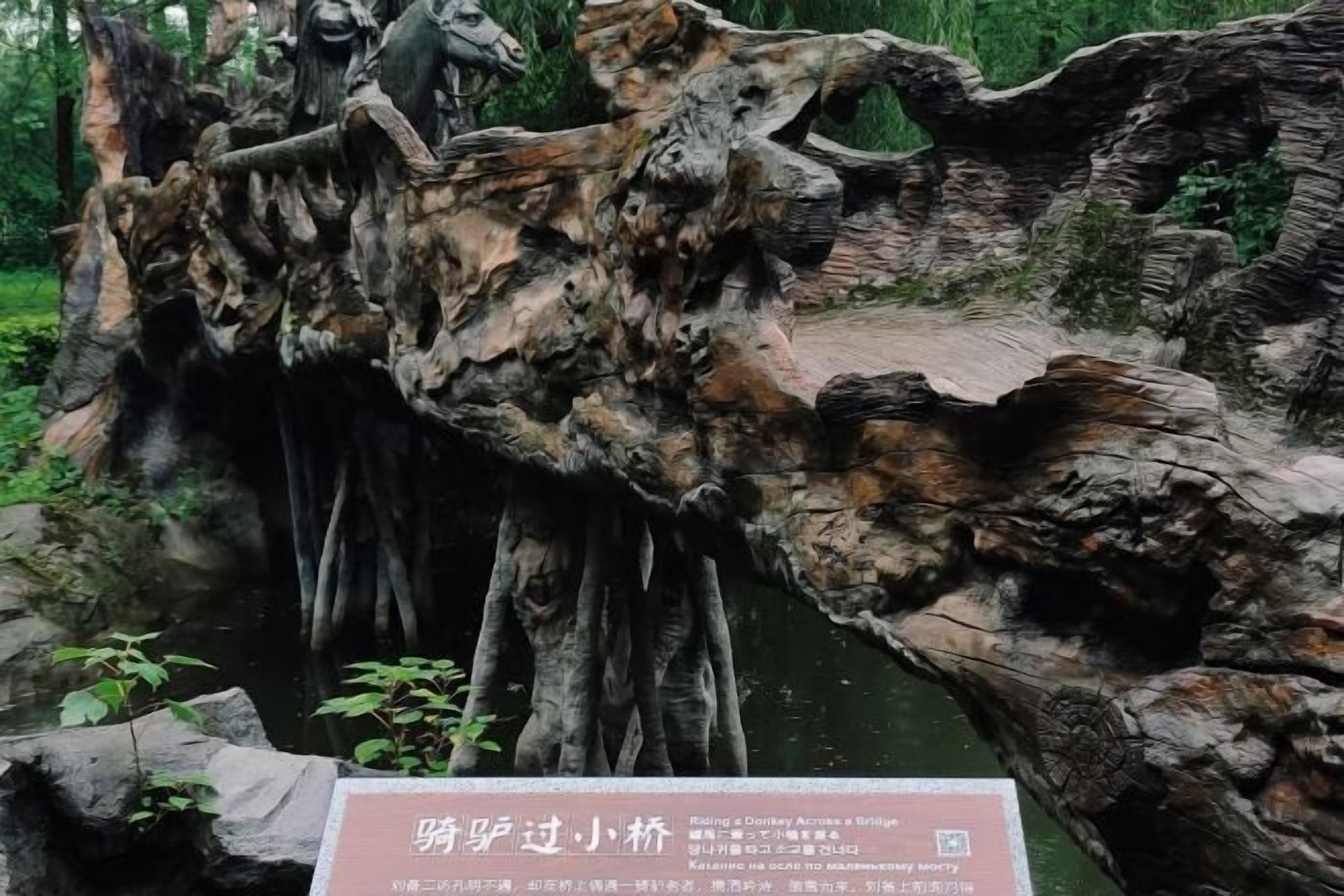 A naturalistic rock formation with a small bridge and a sign in a forested area.