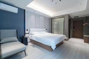 Una habitación de hotel moderna con cama, una silla, mesita de noche y armario.