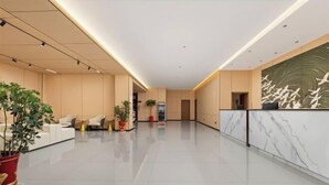 A modern hotel lobby with a reception desk, seating area, and potted plants. - Chibi Lake Holiday Hotel (Xinjiekou Commercial Street) (Chibi)