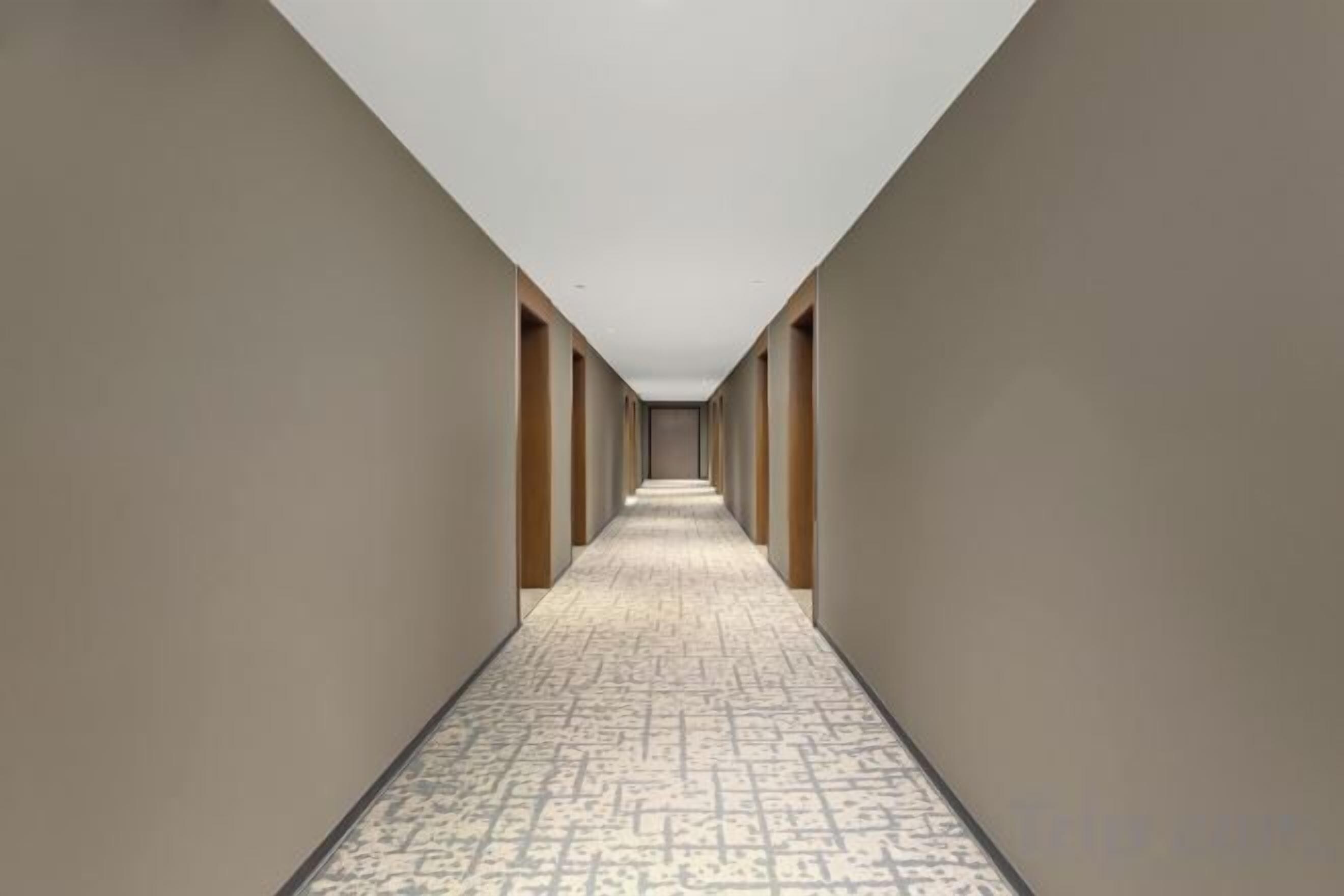 Un pasillo con piso estampado y paredes, que conduce a una puerta al final.