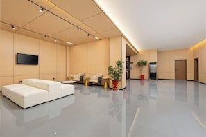 A modern lobby with a white sofa, seating area, and a flat-screen TV. - Chibi Lake Holiday Hotel (Xinjiekou Commercial Street) (Chibi)