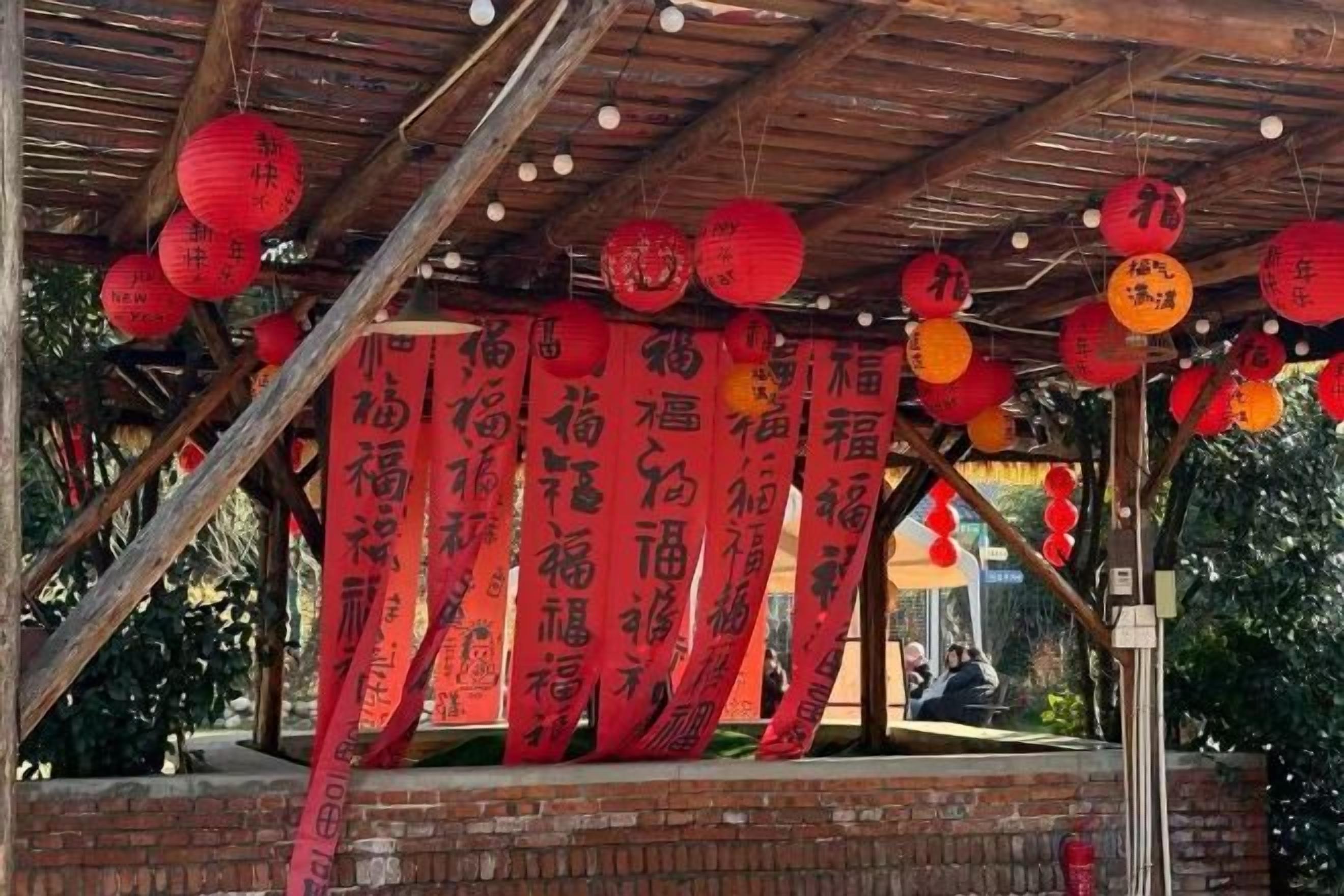 A covered outdoor area with red banners and hanging lanterns.