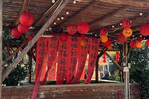 A covered outdoor area with red banners and hanging lanterns.