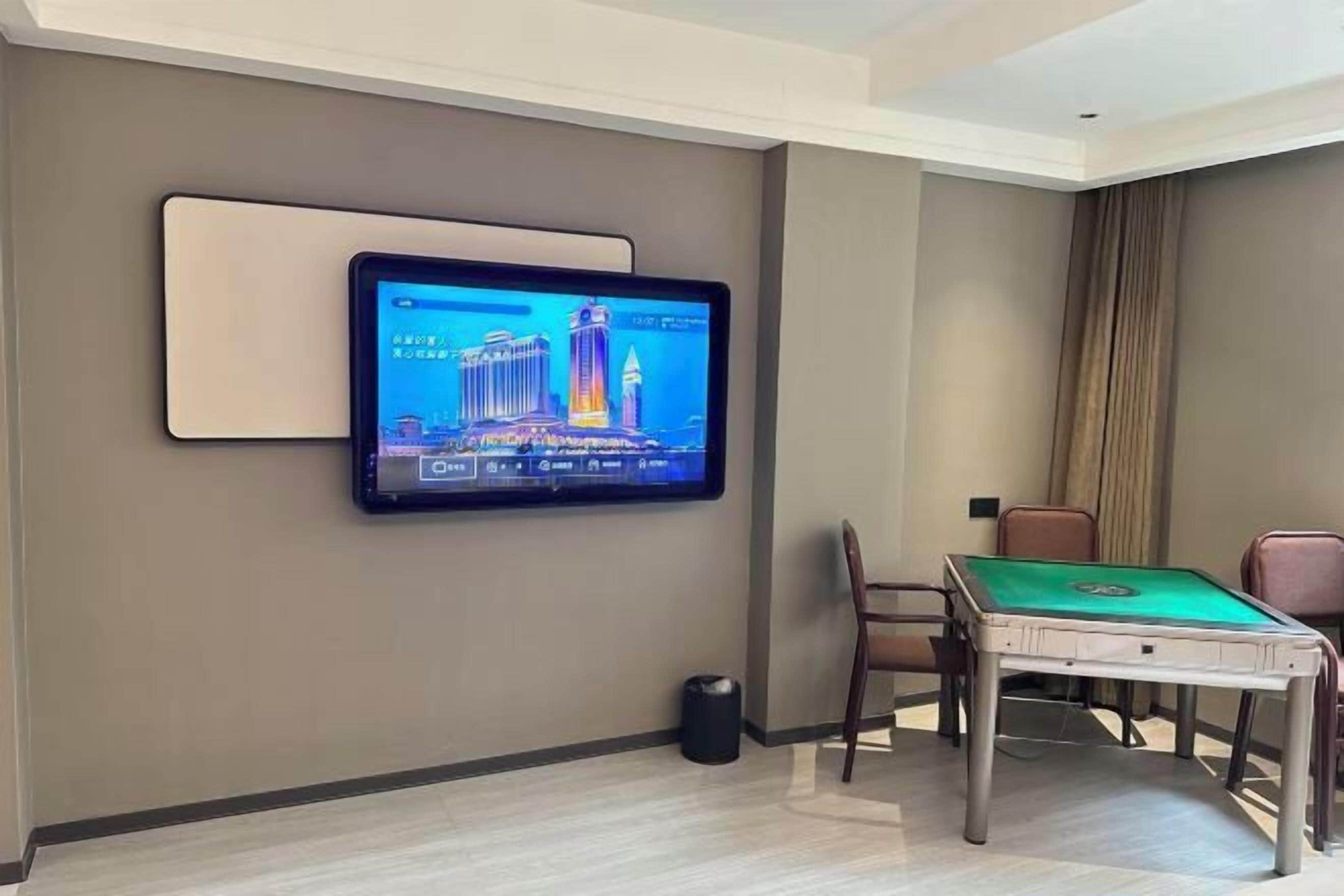 Habitación de hotel con televisor de pantalla montado que muestra un paisaje urbano, una mesa de billar y una zona de estar.