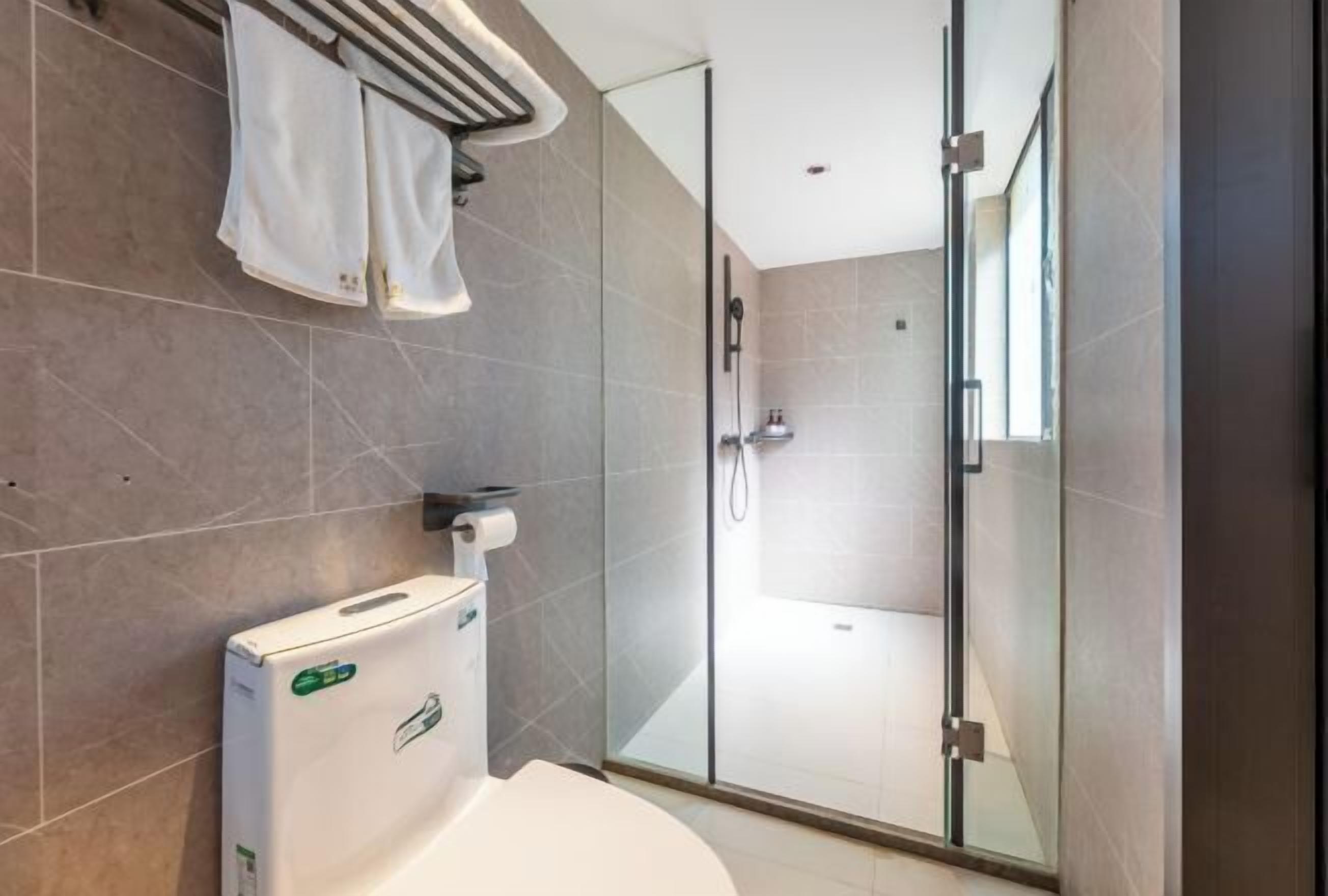 Et moderne badeværelse med toilet, glas brusekabine og håndklædestang.