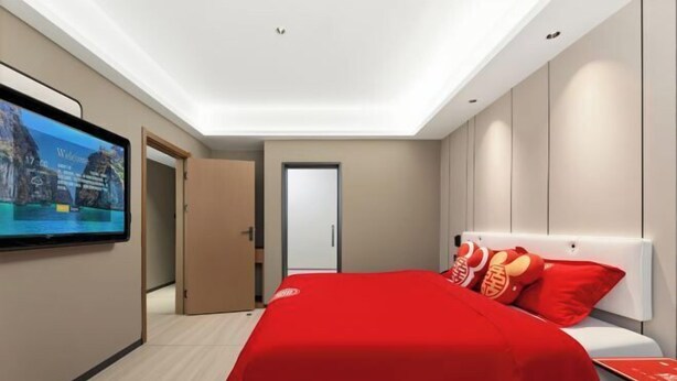 Una habitación de hotel moderna con una cama grande, un televisor en la pared y una puerta que da a otra habitación.