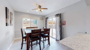 A dining area with a table and chairs, a ceiling fan, and a view through a large window. - Bright & Cozy Upper Unit in Denver (Denver)