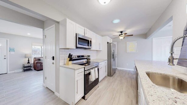 A modern kitchen with white cabinetry, a stainless steel sink, and a ceiling fan. - Bright & Cozy Upper Unit in Denver (Denver)