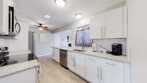 A modern kitchen with white cabinets, a stainless steel dishwasher, and a granite countertop. - Bright & Cozy Upper Unit in Denver (Denver)