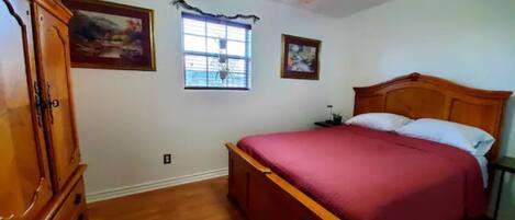 Un dormitorio con una cama de madera, un ventilador de techo y dos cuadros en la pared.
