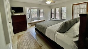 A bedroom with a bed, a ceiling fan, a window seat, and a TV. - Private Forest Cabin with Wrap-Around Deck, Fireplaces & Unlimited Hiking (Payson)