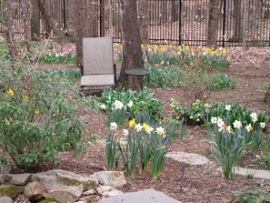 Sit and enjoy the serene garden surroundings with a metal chair and small table near a tree.