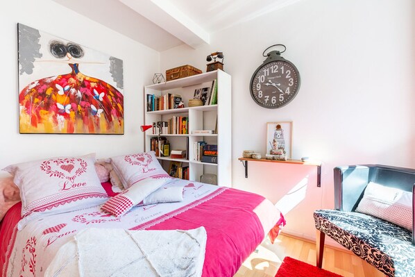 A bedroom with a bed, a bookshelf, a clock, and a chair.