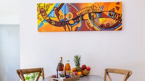 A dining area with a round table, two wooden chairs, and a colorful abstract painting on the wall. - ❤ LE COCON ❤ Centre Historique ➡ STUDIO TOUT INCLUS ★ (Strasbourg)