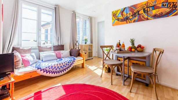 A modern living room with a sofa, a dining table with chairs, a TV, and a painting on the wall. - ❤ LE COCON ❤ Centre Historique ➡ STUDIO TOUT INCLUS ★ (Strasbourg)