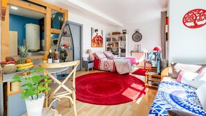 A modern living room with a red rug, wooden furniture, a bookshelf, and a wall clock. - ❤ LE COCON ❤ Centre Historique ➡ STUDIO TOUT INCLUS ★ (Strasbourg)