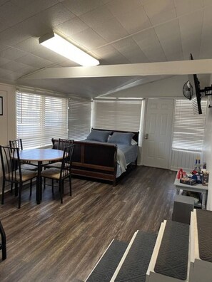 A compact room with a bed, a dining table with chairs, and a small kitchenette area. - Little Red Lake House (Greers Ferry)
