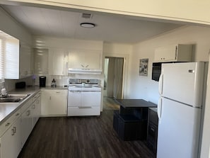 A compact kitchen with white cabinetry, a built-in oven, a refrigerator, and a sink. - Little Red Lake House (Greers Ferry)