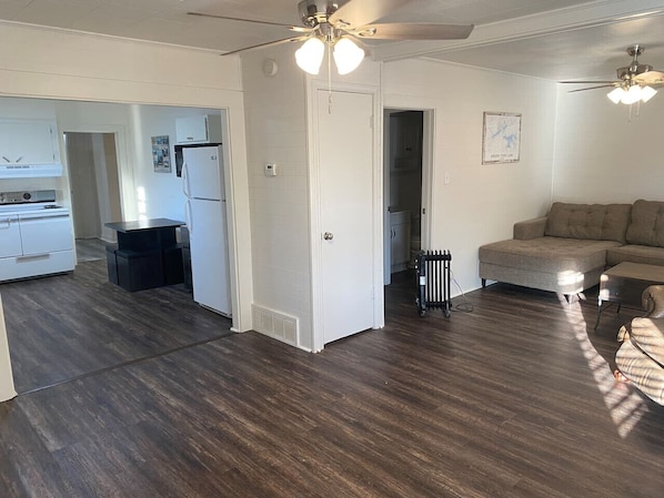 A spacious living area with a dark hardwood floor, a white door, and a ceiling fan. - Little Red Lake House (Greers Ferry)
