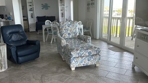 A spacious living area with a large sofa, a chair, and a dining table. - 3 Bed/3 Bath ~ 2nd Floor Oceanfront Prime Condo ~ Elevator ~ 1205 Queens Court (Emerald Isle)