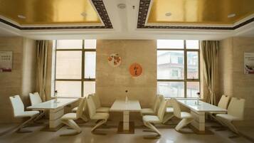 Un salón de conferencias con una larga mesa y sillas, ventanas grandes y una pared decorativa.