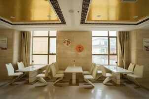 Un salón de conferencias con una larga mesa y sillas, ventanas grandes y una pared decorativa.