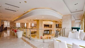 A spacious hotel lobby with a curved ceiling, a glass railing, and a pool area. - Best International Hotel (Shangcheng, Xinyang) (Shangcheng)