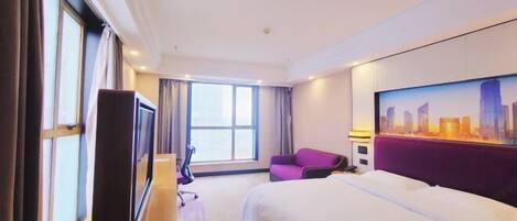 A hotel room with a bed, a desk, a chair, a TV, and a large window.