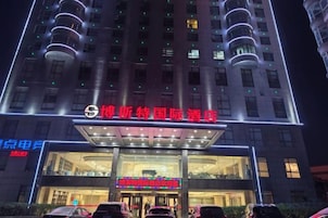 Un hotel con un letrero llamativo, varios pisos y una entrada bien iluminada.