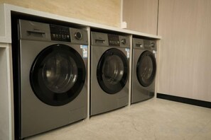A row of three front-loading washing machines in a commercial setting. - Best International Hotel (Shangcheng, Xinyang) (Shangcheng)