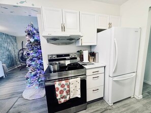 A kitchen with white cabinets, a stainless steel stove, and a white refrigerator.