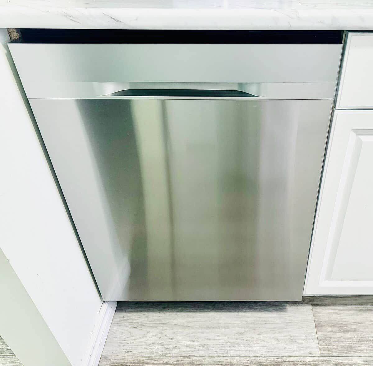 A stainless steel dishwasher in a kitchen with white cabinetry.