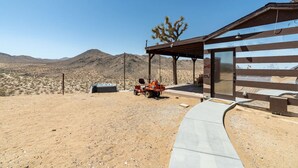 A desert landscape with a building featuring a covered patio and a hot tub. - The Invisible Wind Cabin- Joshua Tree Amazing View (Yucca Valley)