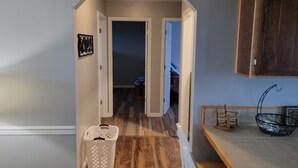 A hallway with wooden flooring, a white laundry basket, and a wooden cabinet. - Norris Lake FarmHouse w/ Lakeviews, access and 140 acres to play. (LaFollette)