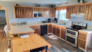 A kitchen with wooden cabinets, a microwave, a coffee maker, a toaster, and an oven. - Norris Lake FarmHouse w/ Lakeviews, access and 140 acres to play. (LaFollette)