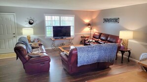 A living room with a television, leather sofas, and a 'Farmhouse' sign on the wall. - Norris Lake FarmHouse w/ Lakeviews, access and 140 acres to play. (LaFollette)