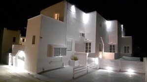 A modern white building with multiple windows and a small balcony. - Louis Residence (Paros)