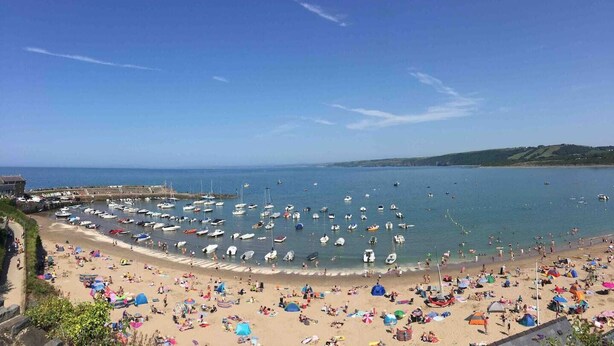 A beach with numerous boats docked and people sunbathing.