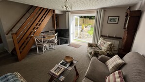 A living room with a wooden staircase, a sofa, a coffee table, and a TV.