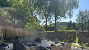 A patio with wicker furniture, a trampoline, and a wooden fence.