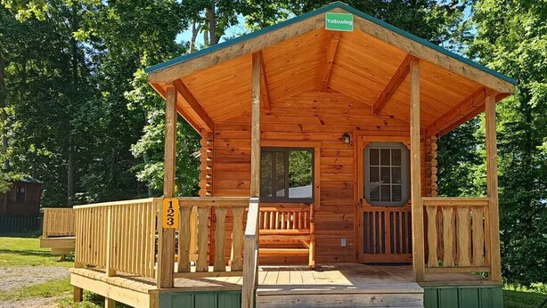 A wooden cabin with a porch, a door, and a window. - 123) Yellowleg Log Cabin. Close to Hocking Hills State Park and more! (Logan)