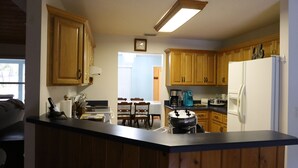 Een keuken met houten kastjes, een koelkast, een koffiezetapparaat en een fornuis.