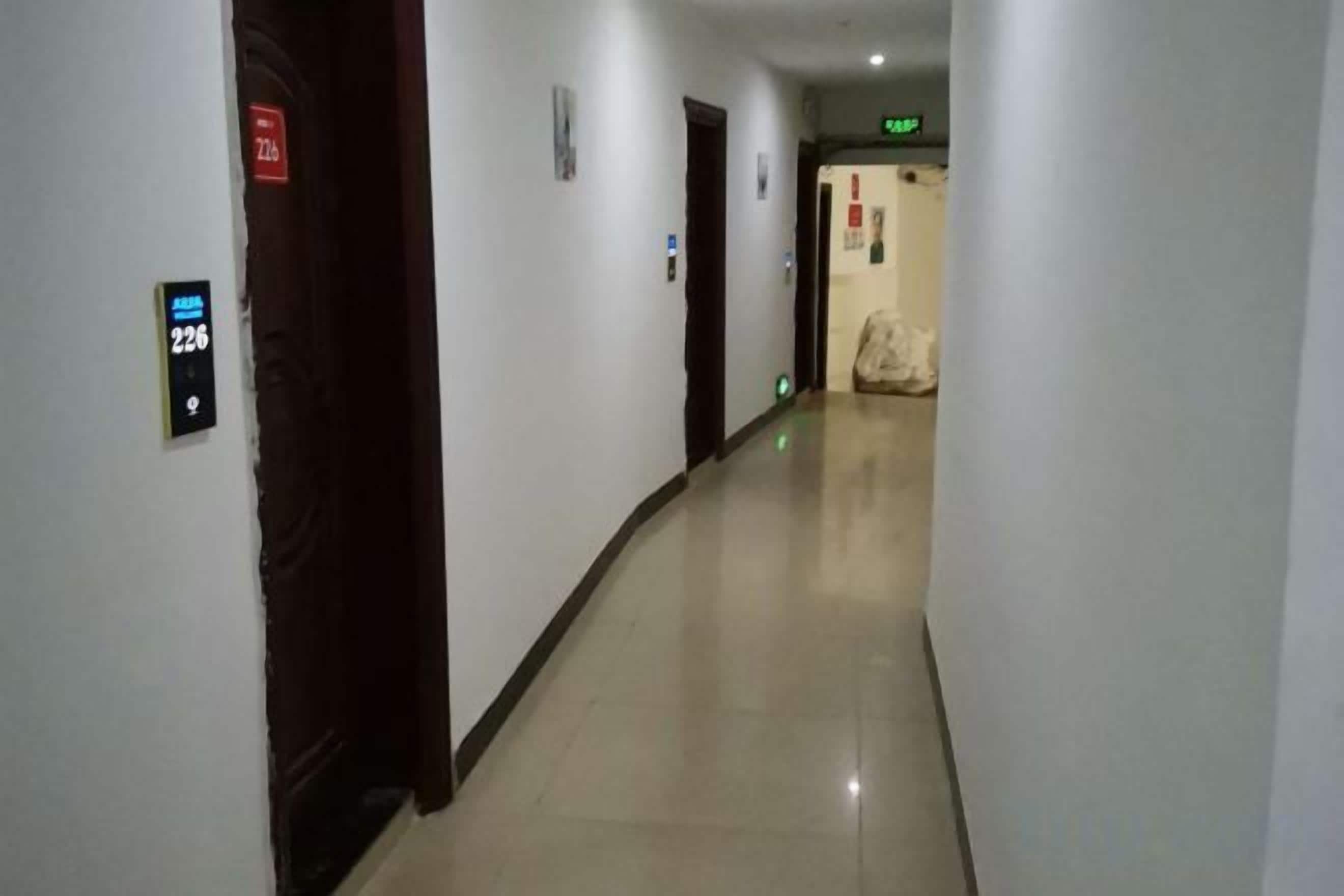 Ein Korridor mit Türen, einem Schild mit der Zimmernummer 226 und einem grünen Ausgangsschild.