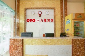 A reception desk with a marble design, a clock, and a sign with the name 'OYO' and Chinese characters. - Bandung Hotel (Wuzhou)