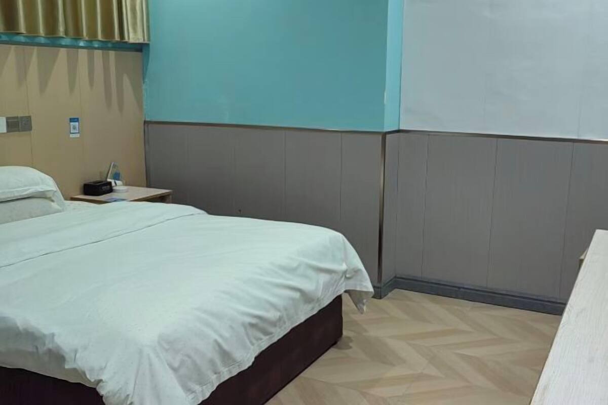 Una habitación de hotel con una cama, una mesita de noche y una lámpara de pared.